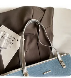 Detail of blue denim tote bag featuring silver metallic straps and a sturdy top handle