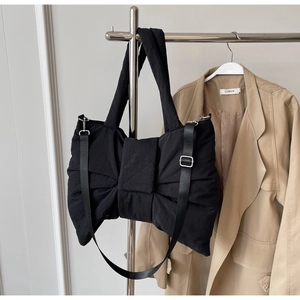Detail of black quilted nylon bow tote with adjustable strap and metal hardware
