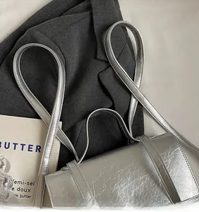 Détail d'un sac argenté métallisé à fines lanières posé sur un blazer gris chic