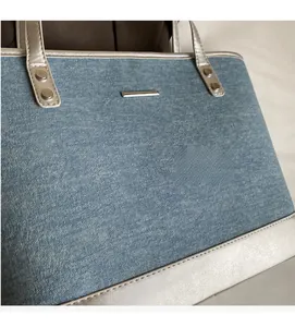 Detail of blue denim tote bag featuring silver metallic trim and woven fabric texture