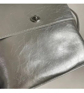 Gros plan sur le tissu métallisé argenté avec fermoir rotatif sur un sac à bandoulière