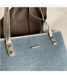 Close-up of denim tote bag featuring silver leather trim and metallic rivet details
