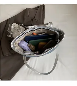Detail showing the large interior capacity of a silver denim tote bag with daily items