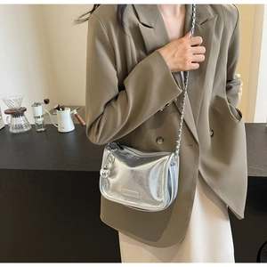 Sac bandoulière argenté avec chaîne et pendentif sphérique porté par un mannequin