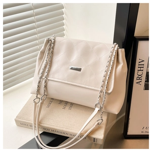 Close-up of cream quilted shoulder bag with silver chain strap and metal lock detail