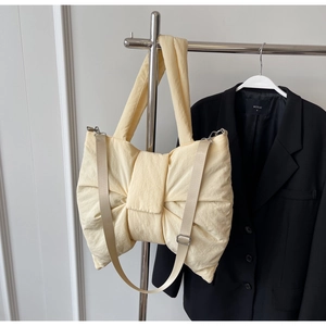 Detail of light yellow bow-shaped tote bag with adjustable strap and textured fabric