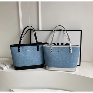 Detail of denim tote bags in light blue with contrasting black and silver leather straps