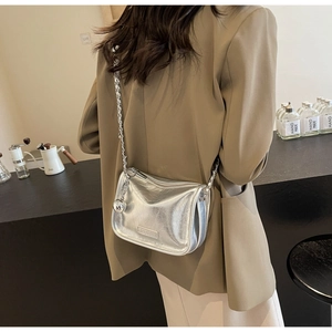Détail d'un sac bandoulière argenté métallisé avec chaîne et breloque boule en métal