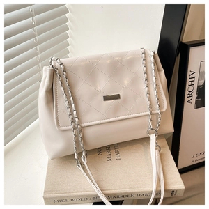 Detail view of cream quilted shoulder bag featuring silver chain strap and metal hardware