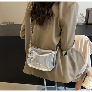 Détail du sac à chaîne argenté à texture froissée sur une tenue de blazer marron