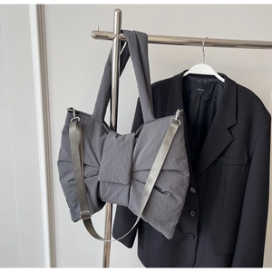 Detail of grey bow-shaped tote bag showing matte nylon texture and adjustable shoulder strap