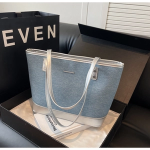 Detail of blue denim tote bag with silver metallic straps in a luxury gift box