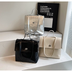 Trois sacs à dos minimalistes en argent, noir et crème sur des marches d'exposition