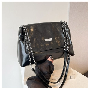 Detail view of black quilted faux leather bag with shiny finish and silver chain strap