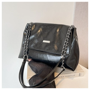 Detail of black quilted leather shoulder bag with silver plaque and chain strap