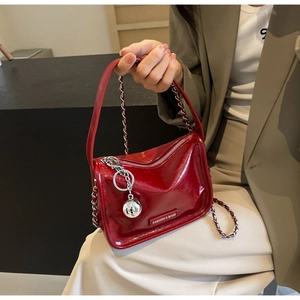 Détail du sac à main rouge en cuir verni avec chaîne argentée et pendentif boule