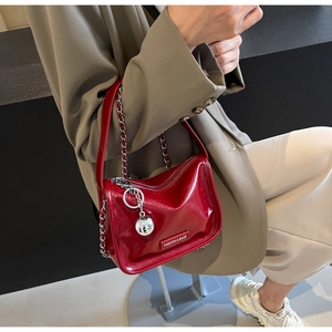 Détail d'un sac à main rouge brillant avec chaîne argentée et breloque boule