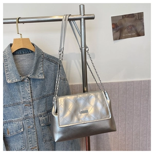 Detail of silver quilted shoulder bag featuring glossy finish and metal chain strap