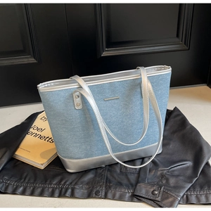 Detailed view of denim tote bag with silver metallic trim on a fashion magazine