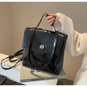 Détail du sac en cuir brillant noir avec fermoir rotatif argenté et poignée haute