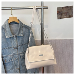 Detail of beige quilted patent leather shoulder bag with silver chain and metal plaque