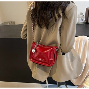 Détail du sac à chaîne rouge brillant avec garnitures argentées sur un blazer kaki