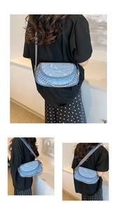 Detail of blue denim hobo bag with silver chain strap and leather trim accents