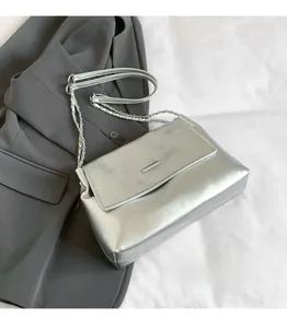 Macro detail of silver quilted bag with metallic clasp and chain strap on grey blazer