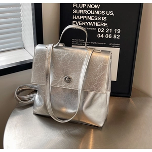 Détail d'un sac à dos argenté métallisé avec serrure rotative en métal et poignée supérieure