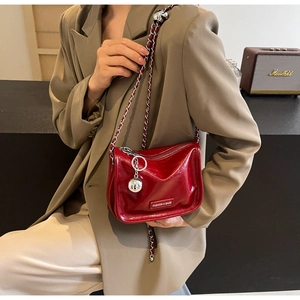 Détail du sac bandoulière rouge en cuir verni brillant avec chaîne argentée et breloque miroir