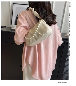 Detail of off-white ruched dumpling bag featuring an elegant pearl chain shoulder strap
