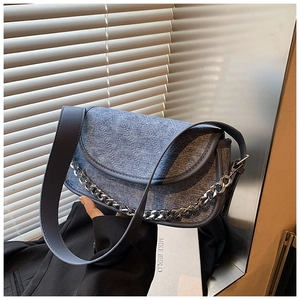 Detail view of denim texture, diamond stitching, and silver chain strap on underarm bag