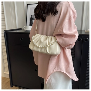 Close-up of white ruched cloud bag featuring decorative large pearl handle and soft leather texture
