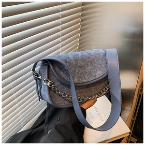 Detail of blue denim shoulder bag with V-quilted texture and silver chunky chain strap