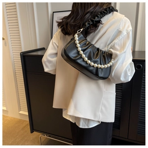 Close-up of black pleated cloud bag with elegant pearl chain and soft leather strap