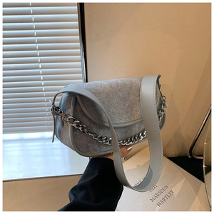Detail of gray-blue denim underarm bag with wavy quilting and silver chain strap