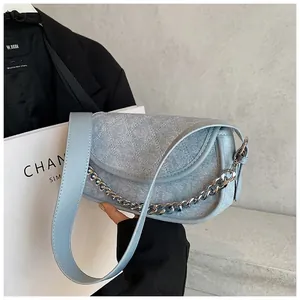 Detail view of quilted denim blue dumpling bag with chunky silver chain and wide strap