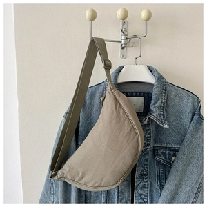 Khaki crescent crossbody bag on a blue denim jacket background with adjustable strap