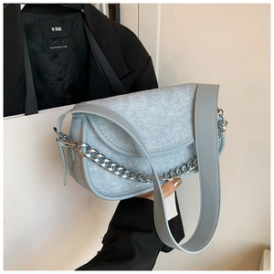 Detail of light blue denim texture shoulder bag with silver chain and quilted flap