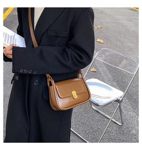 Detailed view of the classic gold buckle on a retro brown leather shoulder bag