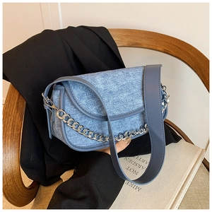 Detail of light blue denim saddle bag with silver metal chain and quilted pattern