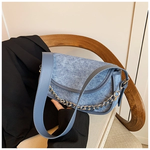 Detail view of light blue denim dumpling bag with diamond quilting and silver chain