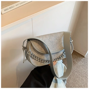 Detail of light gray quilted hobo bag with thick metal chain and wide leather strap