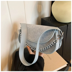 Detail of light blue denim flap bag with quilted diamond pattern and silver chain strap