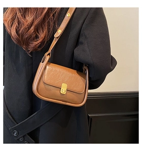 Detailed view of caramel leather crossbody bag with elegant gold magnetic lock buckle