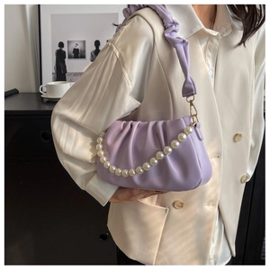 Detail of lavender pleated cloud bag featuring pearl chain strap and gold hardware accents