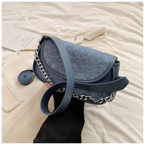 Detail of blue denim shoulder bag featuring quilted stitching and silver chain strap