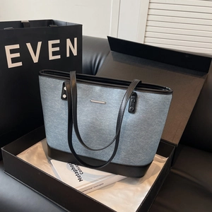 Large denim tote bag with leather straps and metal detail, presented in a gift box