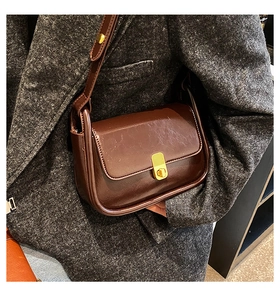 Detail of dark brown vintage crossbody bag with gold metallic lock on tweed jacket