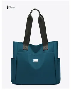 Detail van de blauwe nylon draagtas met zijzakken en zwarte stoffen handgrepen